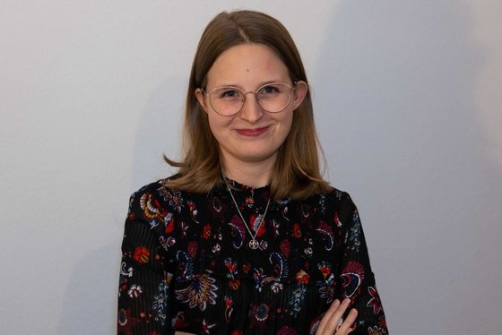 Eine Frau mit schulterlangen Haaren und verschränkten Armen lächelt in die Kamera