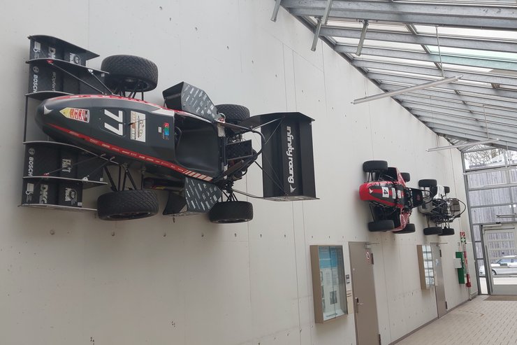 Rennwägen im Gang der Maschinenhalle Rennwägen hängen im Gang der Maschinenhalle an der Wand