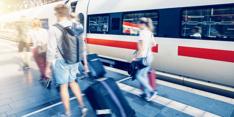 Studierende mit Koffern am Bahnsteig vor einem Zug stehen für grenzenlose Mobilität und internationale Studienmöglichkeiten