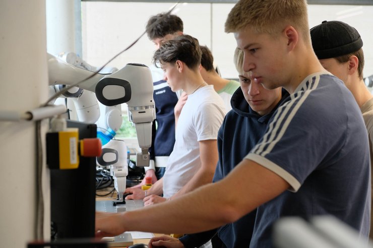 Mehrere Schülerinnen und Schüler nehmen während der Campustage 2026 an einer Laborführung der Hochschule Kempten teil. Gemeinsam beobachten und bedienen sie einen Industrieroboter und erhalten Einblicke in moderne Automatisierungs- und Produktionstechnik. Die Szene vermittelt praxisnahe Studienorientierung und zeigt, wie Jugendliche aktuelle Technologien direkt auf dem Campus kennenlernen und selbst ausprobieren können.