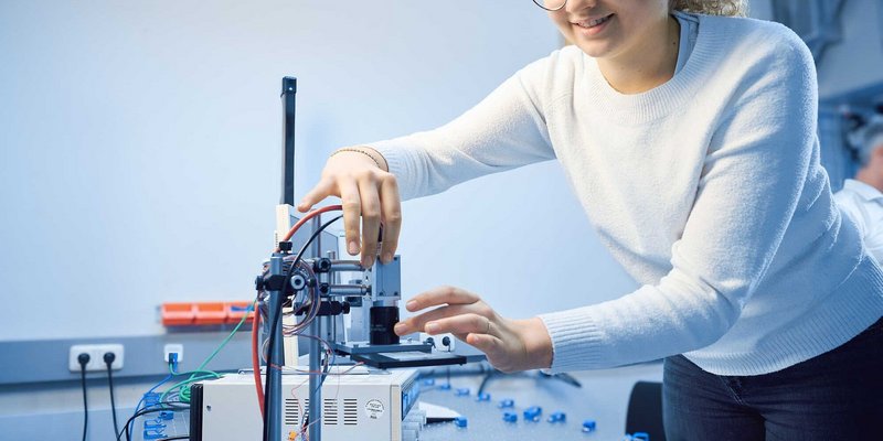 Studentin führt eine technische Messung oder einen Aufbau in einem Labor durch
