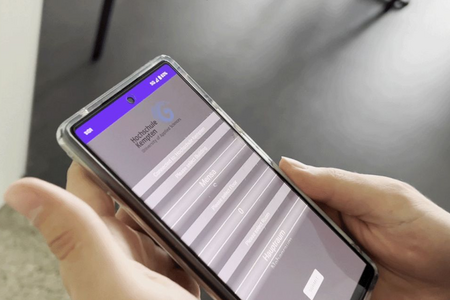 Start-Screen auf dem Smartphone, das eine Person in der Hand hält.
