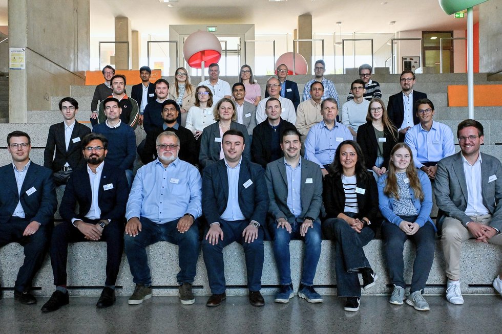 Gruppenfoto der Teilnehmenden des RESURRECTION-Kick-offs an der Hochschule Kempten. Mehr als 30 Fachleute aus Wissenschaft und Industrie sitzen und stehen gemeinsam auf einer Treppe im Hochschulgebäude.