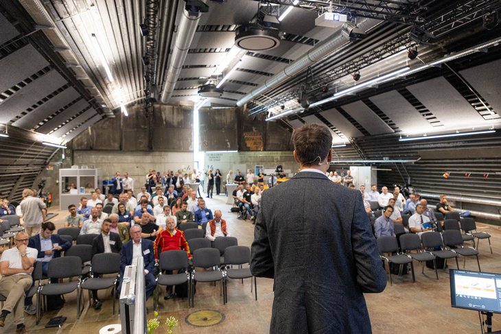 Eine Person vor einer Audienz auf Stühlen in einem Hangar