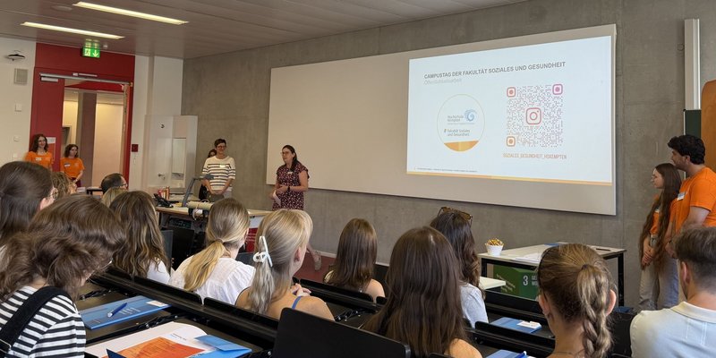 Die Studierenden sitzen im Hörsaal und bekommen im Rahmen des Campustages der Fakultät Soziales und Gesundheit Informationen via PowerPoint-Präsentation von der Dekanin Astrid Selder vermittelt.