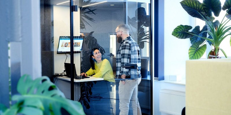 Zwei Personen im modernen Büro im Gespräch vor Glasbüro