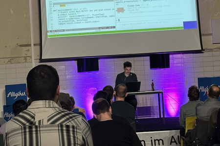 Gespannte Zuhörer, die das Live-Coding von Tom Stadelmann an der großen Leinwand verfolgen.