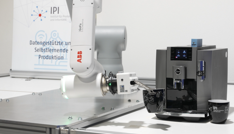 Ein Roboterarm greift eine Tasse Kaffee von einer Kaffeemaschine