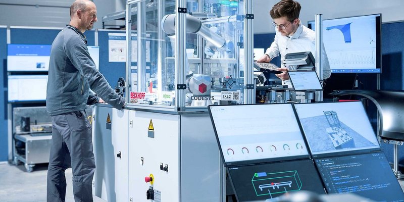 Zwei Personen arbeiten an einer automatisierten technischen Steuerungseinheit