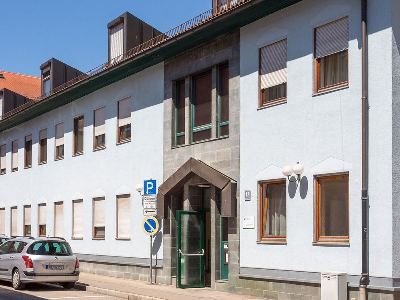 Blick auf ein weisses, dreistöckiges Studierendenwohnheim mit vielen Fenstern und offener Eingangstür