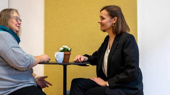 Zwei Personen unterhalten sich an einem runden Tisch