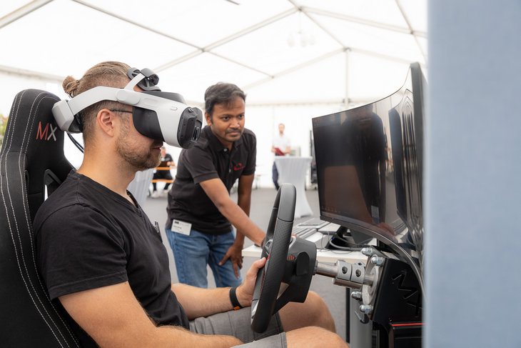 Eine Person mit Virtual Reality Brille an einem Fahrsimulator 