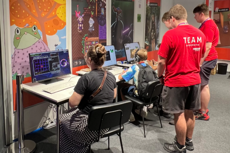 An den drei Computerplätzen testen Messebesucher die Spiele, angeleitet von drei Studierenden.