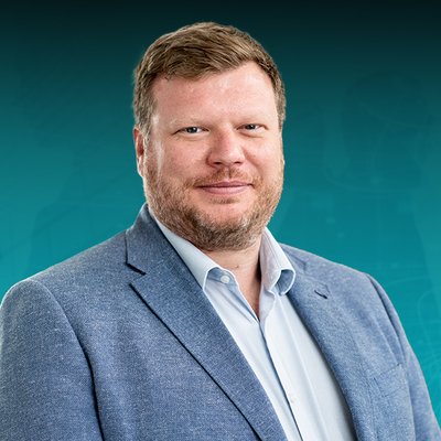Ein Mann mit kurzen braunen Haaren in einem hellblauen Anzug 