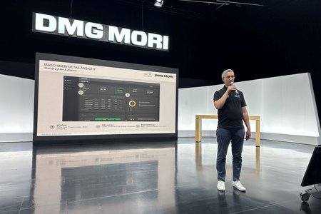 Prof. Dr. Wind spricht mit Mikrofon zum Publikum, im Hintergrund die Leinwand mit einer Maschinendetailansicht.