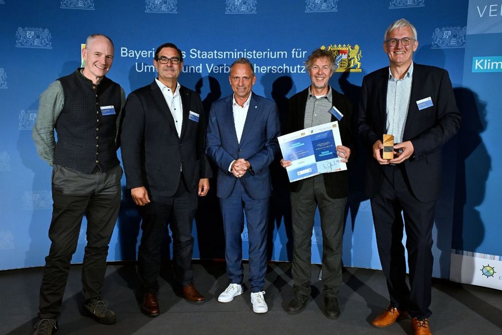 ayerns Umwelt- und Verbraucherschutzminister Thorsten Glauber überreicht den Bayerischen Klimaschutzpreis 2026 an das Team von power2move. Von links: Prof. Dr. Martin Steyer, Martin Haslsch, Thorsten Glauber, Norbert Grotz, Helmut Berchtold. [Foto: Bayerisches Staatsministerium für Umwelt und Verbraucherschutz]