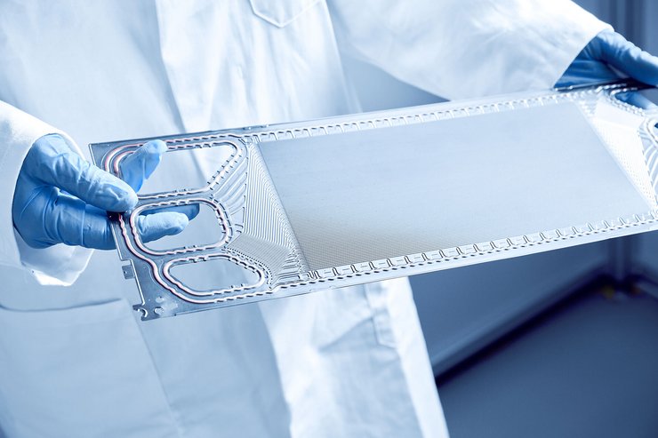 Zwei blaue Einmalhandschuhe tragende Hände halten eine Brennstoffzelle. 