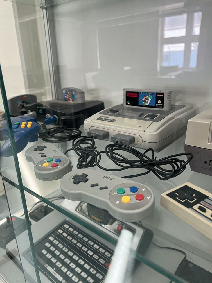 Vitrine mit alten Spielekonsolen wie Super Nintendo mit Controllern und Spielen