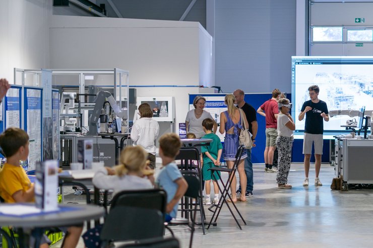 Personen in einer Halle mit Ständen 