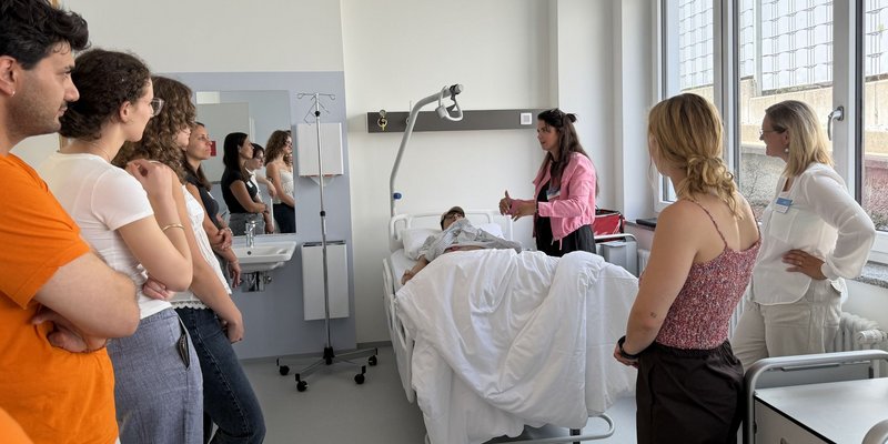 Teilnehmende des Campustages der Fakultät Soziales und Gesundheit schauen sich das Pflegebett inklusive Simulationspuppe in unserem Skills- und Simulationslabor an.