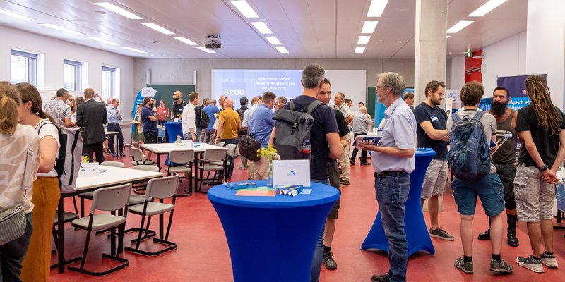 In einem großen Raum stehen viele kleine Personengruppen und unterhalten sich