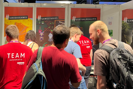 Messebesucher und Studierende in Gesprächen am Messestand.