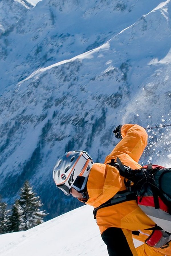 Eine Person carvt auf Ski durch den Pulverschnee