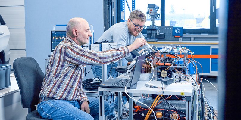 Zwei Personen arbeiten gemeinsam an einem technischen Aufbau im Labor der Hochschule Kempten