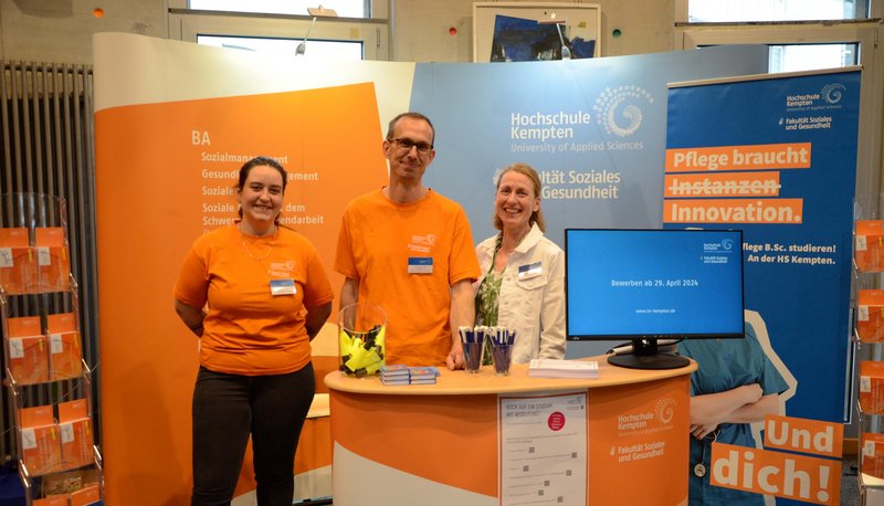 Drei Personen am Informationsstand der Fakultät Soziales und Gesundheit der Hochschule Kempten.