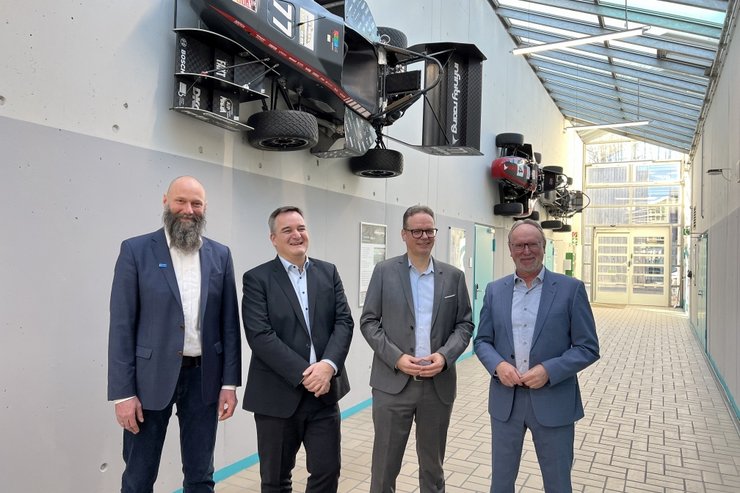 Neu gestalteter Gang der Maschinenhalle an der Fakultät Maschinenbau der Hochschule Kempten –  v. l. n. r.: Prof. Dr. Martin Schirra, Dekan der Fakultät Maschinenbau, Christian Könitzer, Vorsitzender des VDI-Bezirksvereins Augsburg, Prof. Dr.-Ing. Gregor Bischoff, Faculty Advisor des Infinity-Racing-Teams sowie Hochschulpräsident Prof. Dr. Wolfgang Hauke. An der Wand hängen drei Rennwagen. 