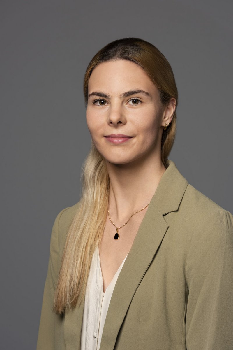Eine Frau mit langen blonden Haaren und khakifarbenen Blazer
