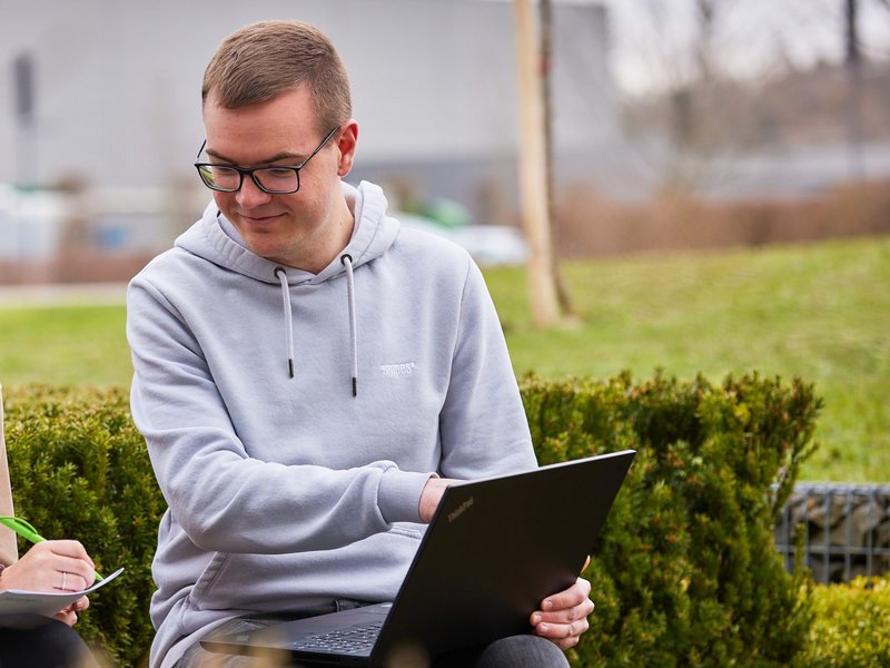 Dominik Fiebig sitzt mit einem Laptop im Freien