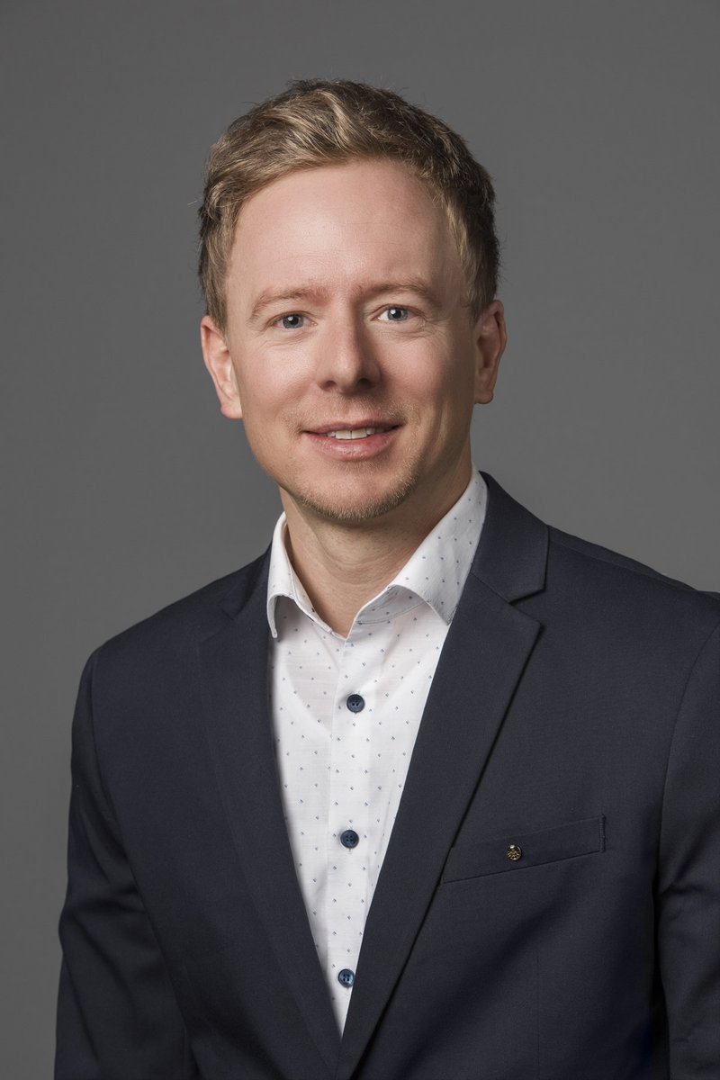 Ein Mann mit kurzen blonden Haaren lächelt in die Kamera
