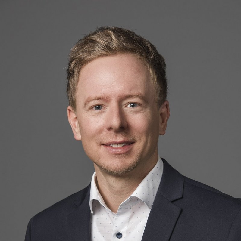 Ein Mann mit kurzen blonden Haaren lächelt in die Kamera