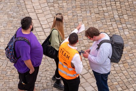Blick von oben auf vier Personen, davon zeigt eine Person den anderen dreien den Weg.