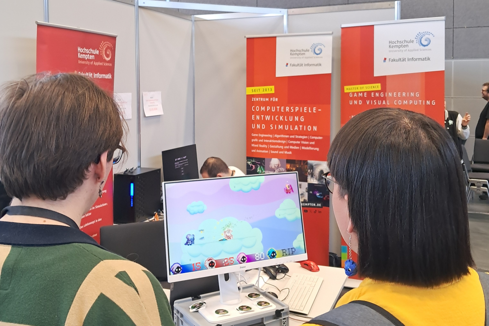 Zwei Studierende spielen ein Computerspiel am Stand der Hochschule Kempten auf der GG Bavaria 2026