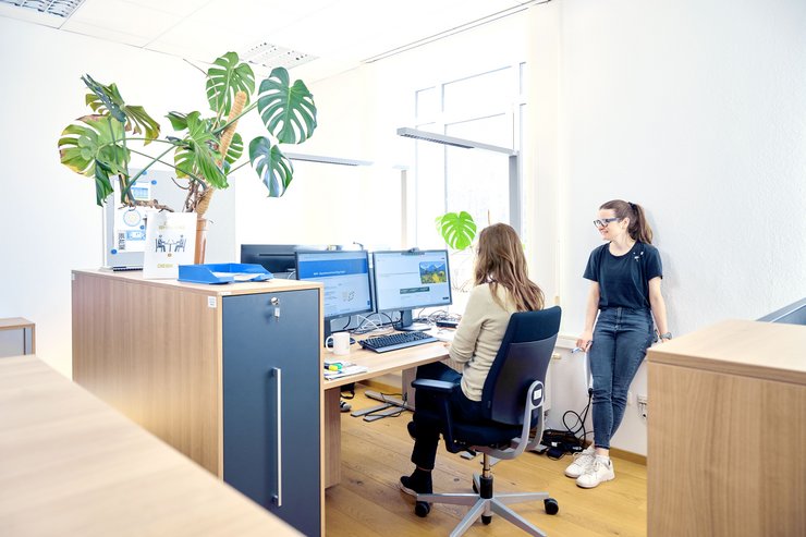 Zwei Personen an einem Schreibtisch in einem lichtdurchfluteten Büro